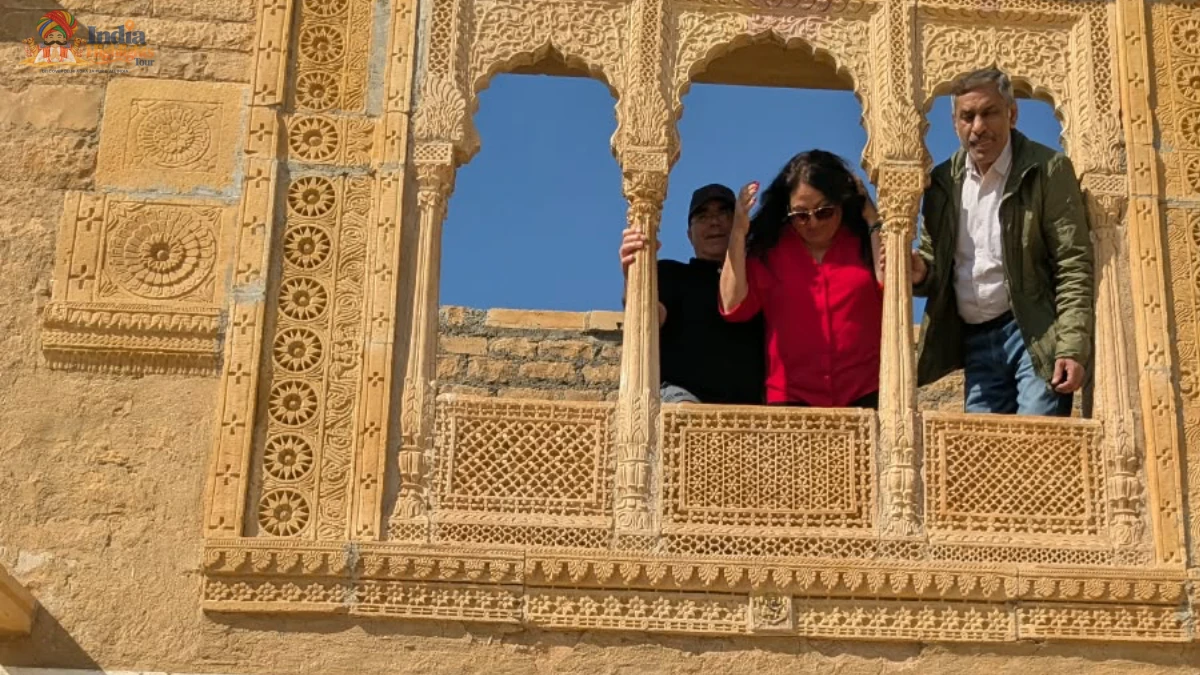 Royal Sandstone Haveli Balcony in Jaisalmer Tourists and guide looking out from an intricately carved yellow sandstone jharokha balcony in Jaisalmer Rajasthan
