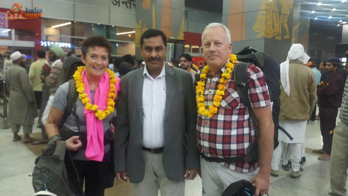Warm Delhi Airport Greeting with Marigold Garlands International travelers with backpacks wearing traditional marigold garlands alongside tour manager at Delhi Airport